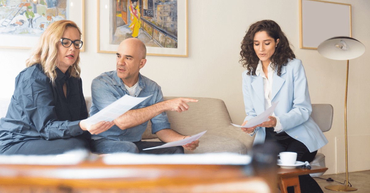 Group of three professionals discussing documents related to property management strategies, seated in a modern office environment, with a focus on effective tenant screening and rental ledger management.