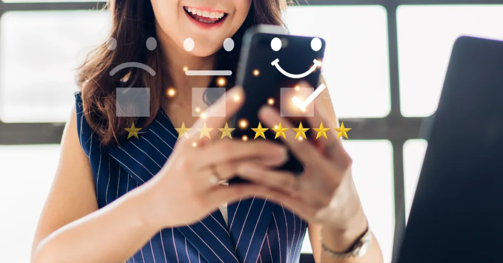 A young woman is holding a phone and giving a five-star rating.