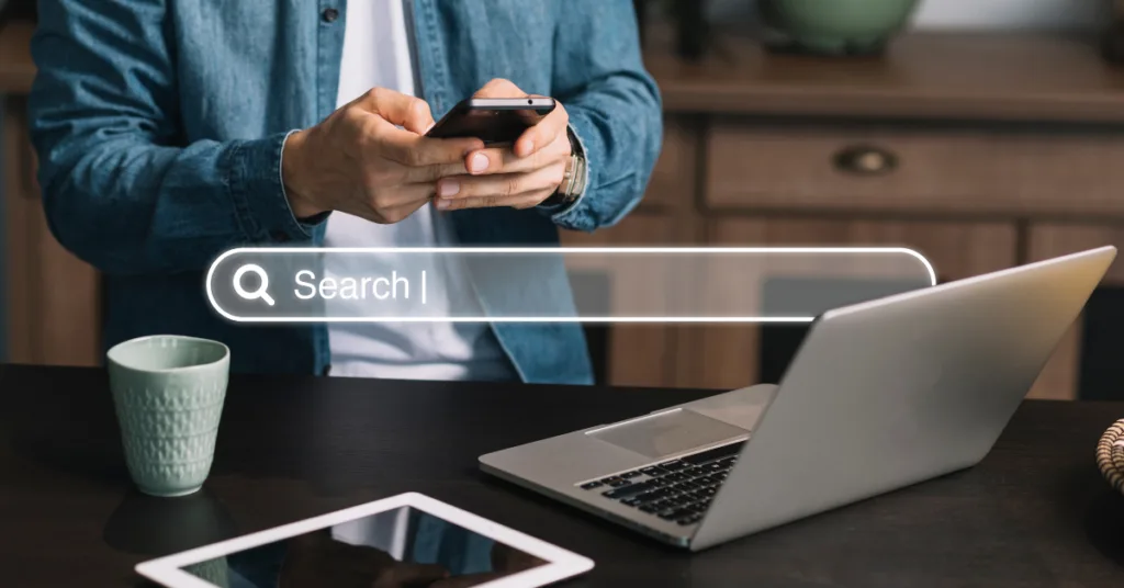 A person is holding a phone with a search bar at the top of the image.