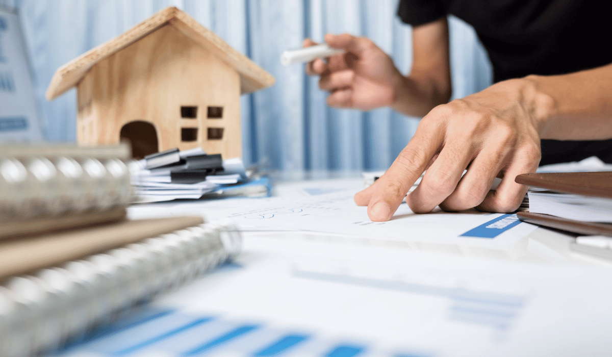 A person is pointing at a house plan while holding a marker