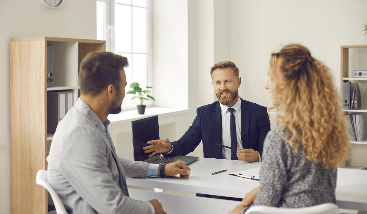 A man and woman are sitting across from a man at a desk