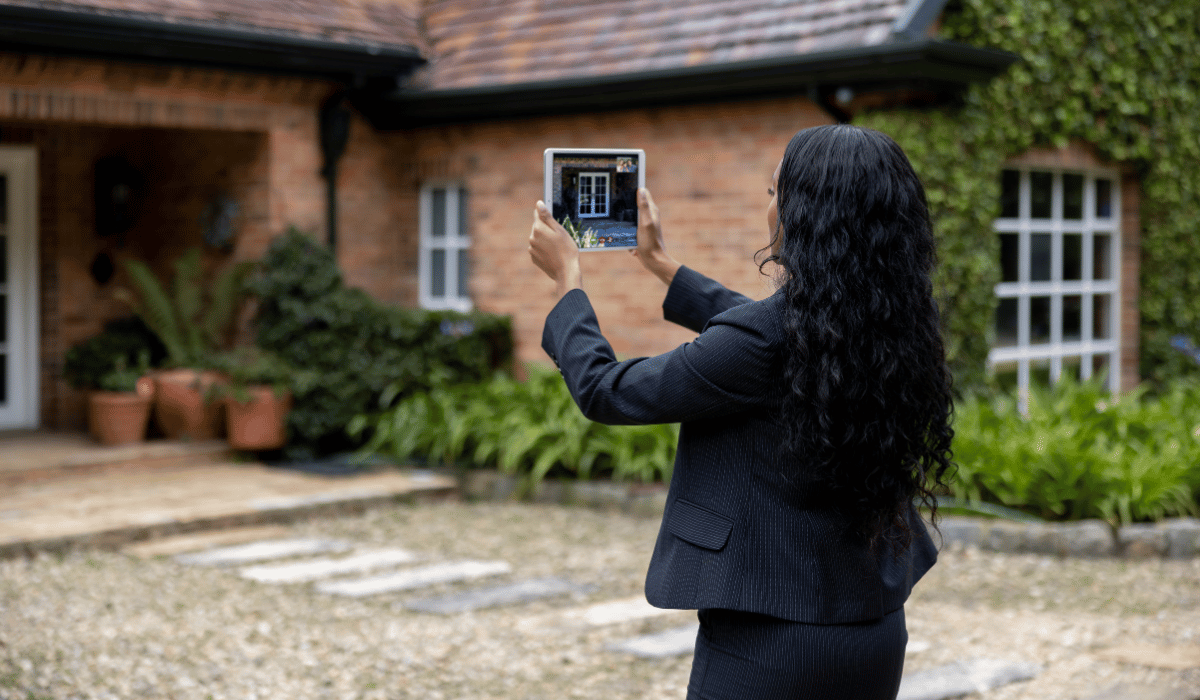 A woman taking a picture of a house.