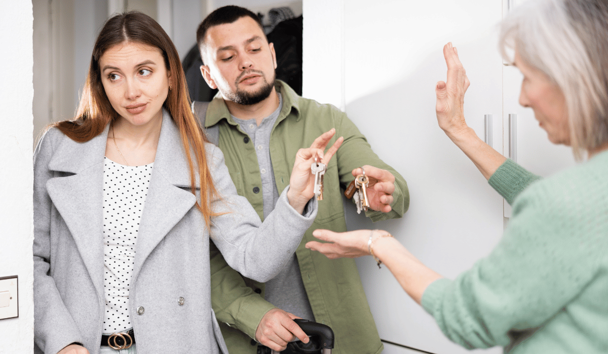 A couple is handing keys to an older woman.