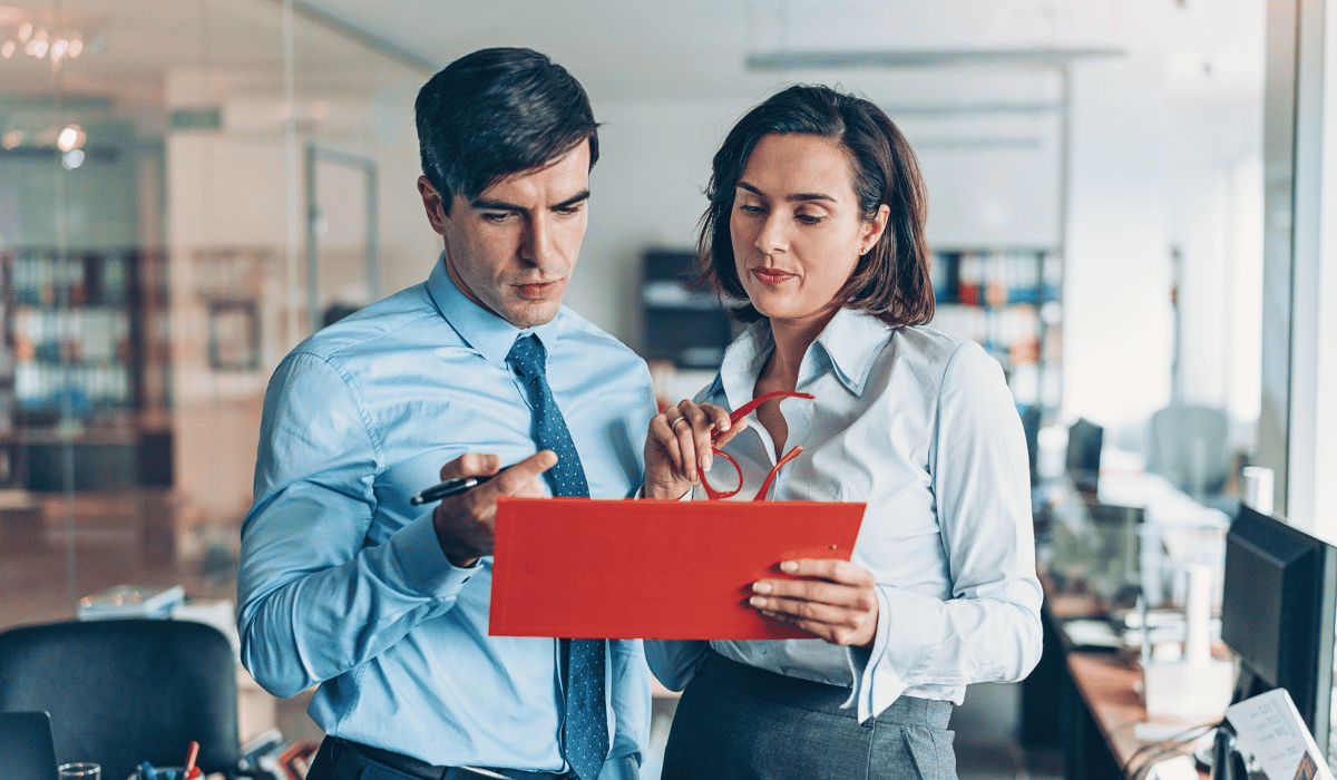 Business professionals reviewing property management strategies with a red document in an office setting.