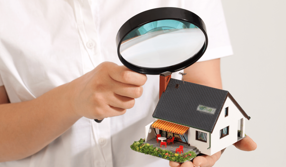 Small model house being examined with a magnifying glass.