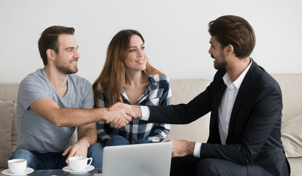 A couple is shaking hands with a real estate agent.