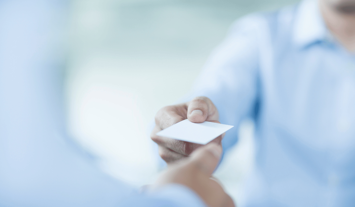 Two people are exchanging a business card.