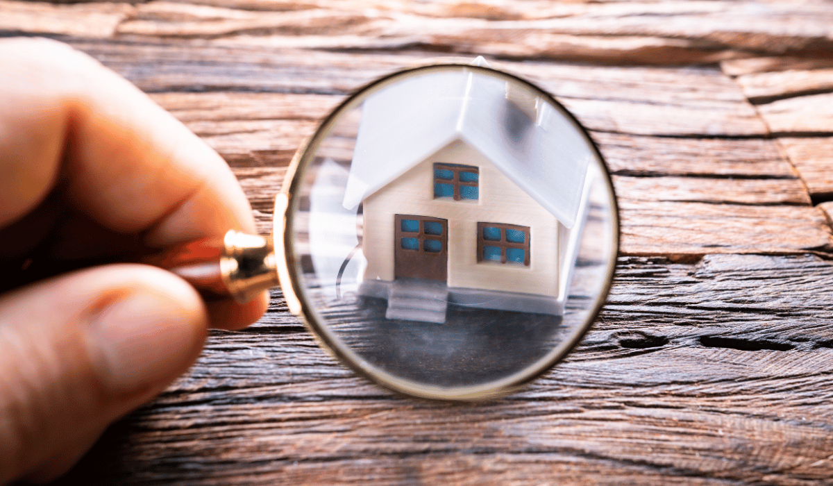 A small house is being viewed through a magnifying glass.