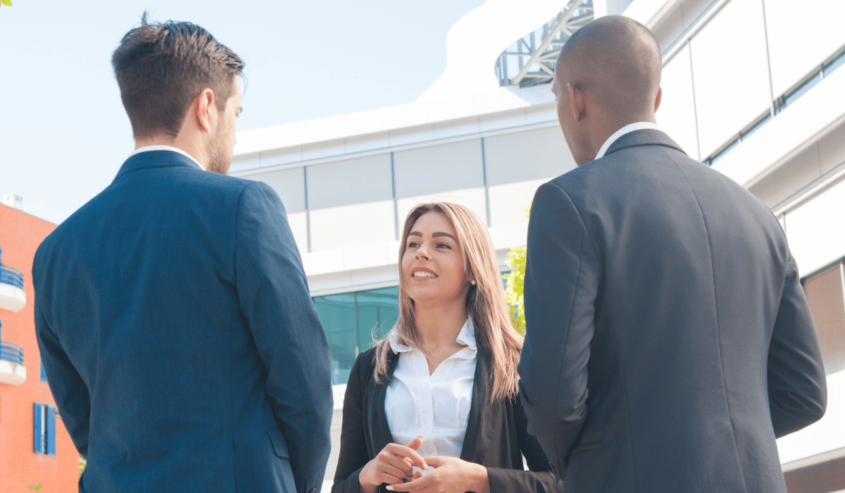 Three business people in suits are talking outdoors