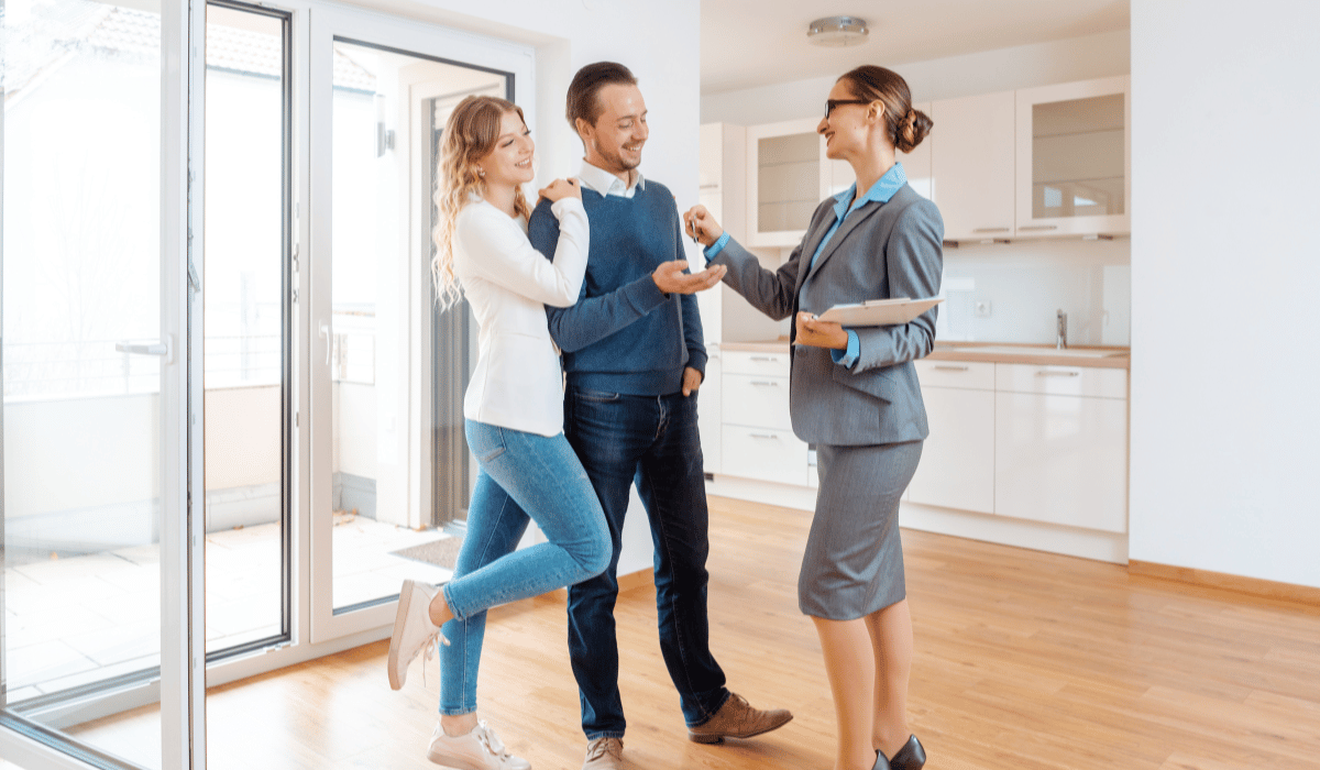 A real estate agent is handing keys to a happy couple.