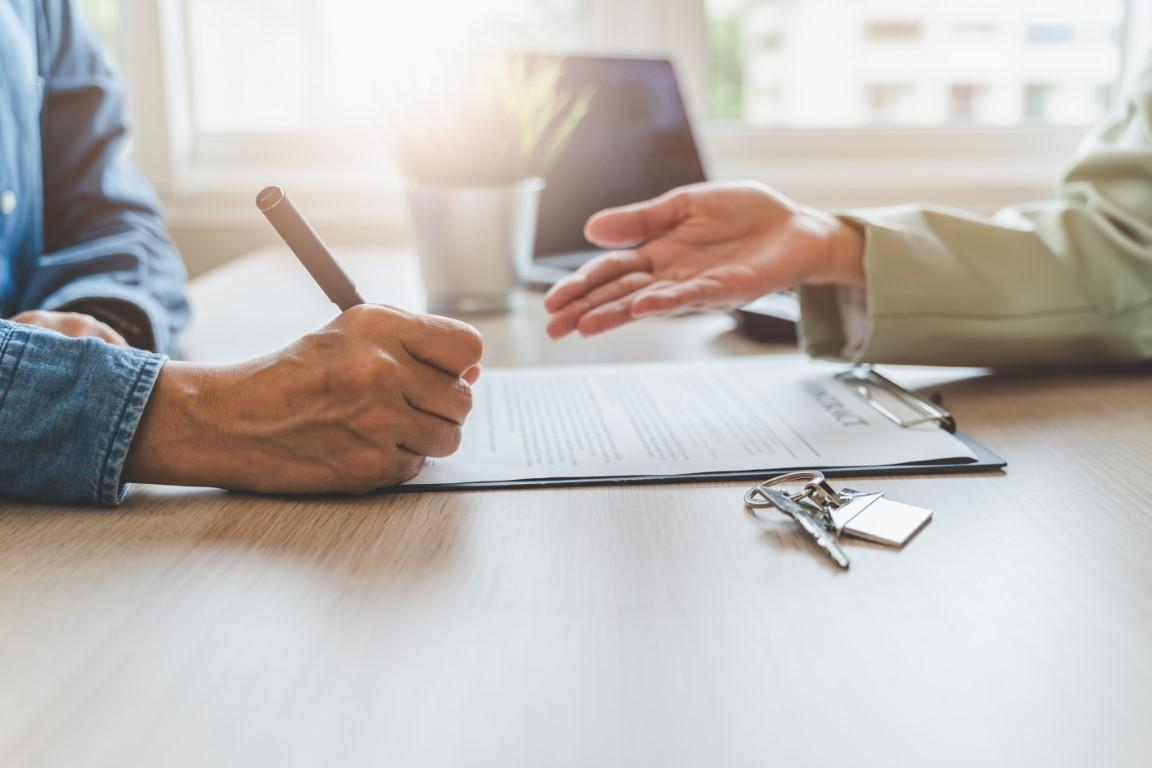 Boston landlord and tenant signing lease agreement at desk with documents and pen in bright professional office