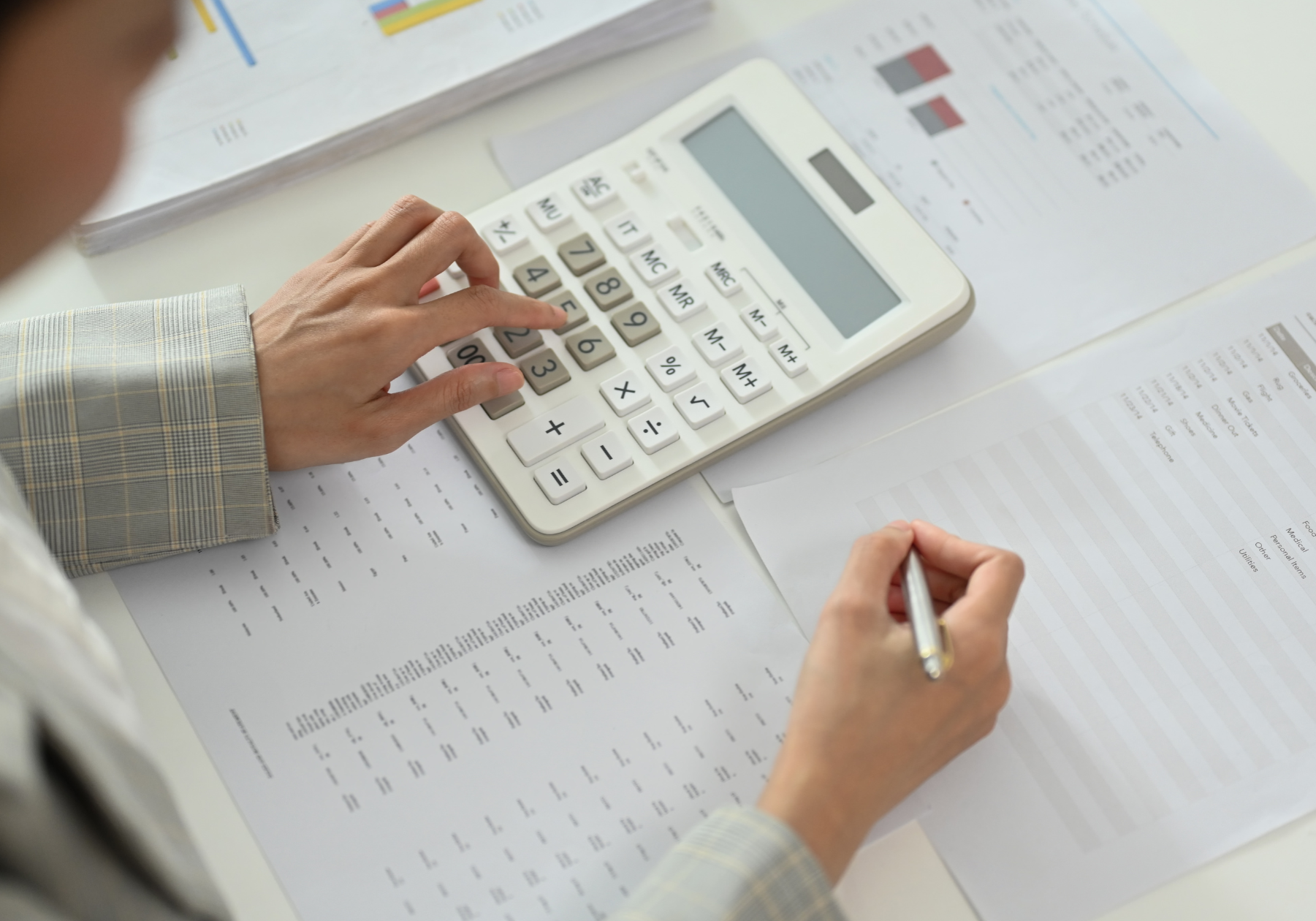 Person using a calculator to manage financial records, surrounded by rental ledger documents and transaction details, emphasizing the importance of accurate payment tracking in property management.